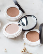Neutral eyeshadow compacts on a white surface.