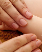 Close-up of a hand gently holding another hand, with a soft focus on the skin texture.