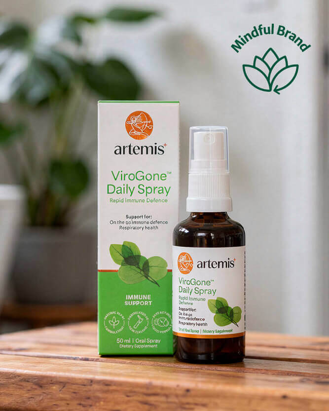 Artemis ViroGone Daily Spray bottle and packaging on a wooden surface with a plant in the background.