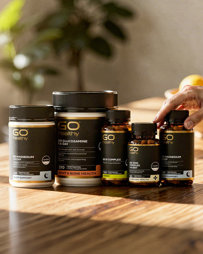 Collection of GO Healthy supplement bottles on a wooden surface with a blurred background