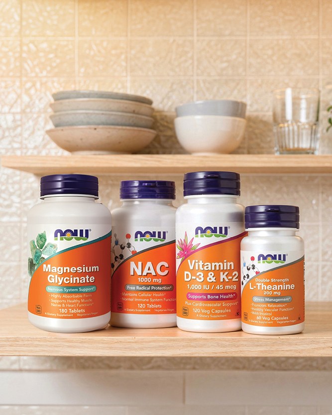 4 NOW Foods products sitting on a wooden kitchen shelf.