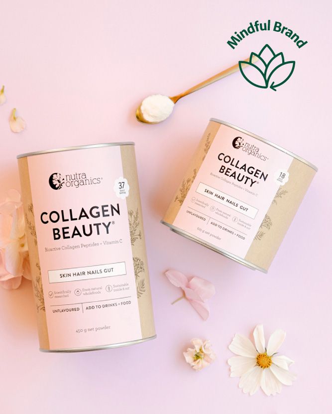 Two canisters of Nutra Organics Collagen Beauty powder are arranged on a soft pink background with decorative flowers, petals, and a wooden spoon. One canister is labeled Collagen Beauty and the other is partially visible with a pink label.