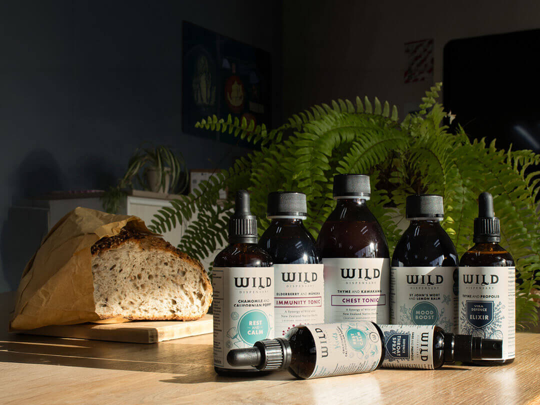Wild Dispensary products on a light surface with a loaf of bread and plant in the background.