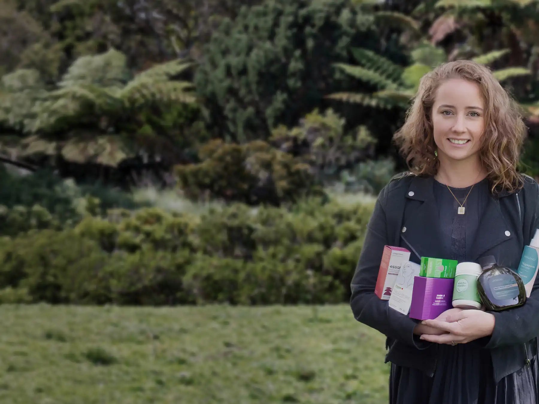 
Person holding colorful items in a grassy field with trees in the background.