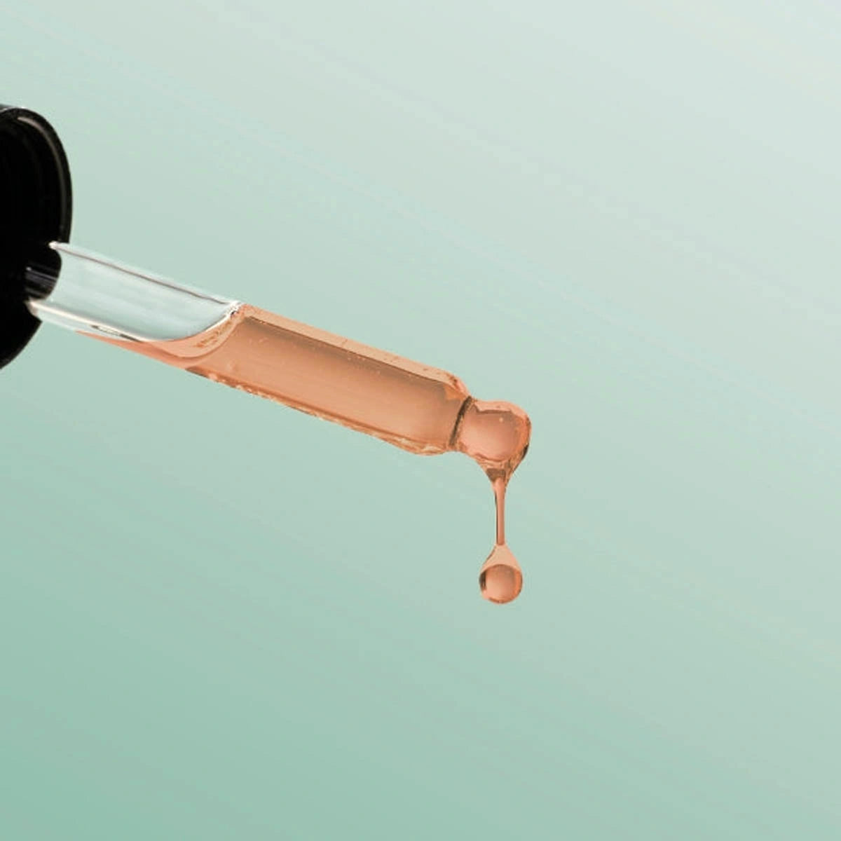 Close up of Lactic Acid Serum dropper with beige liquid on a light blue background