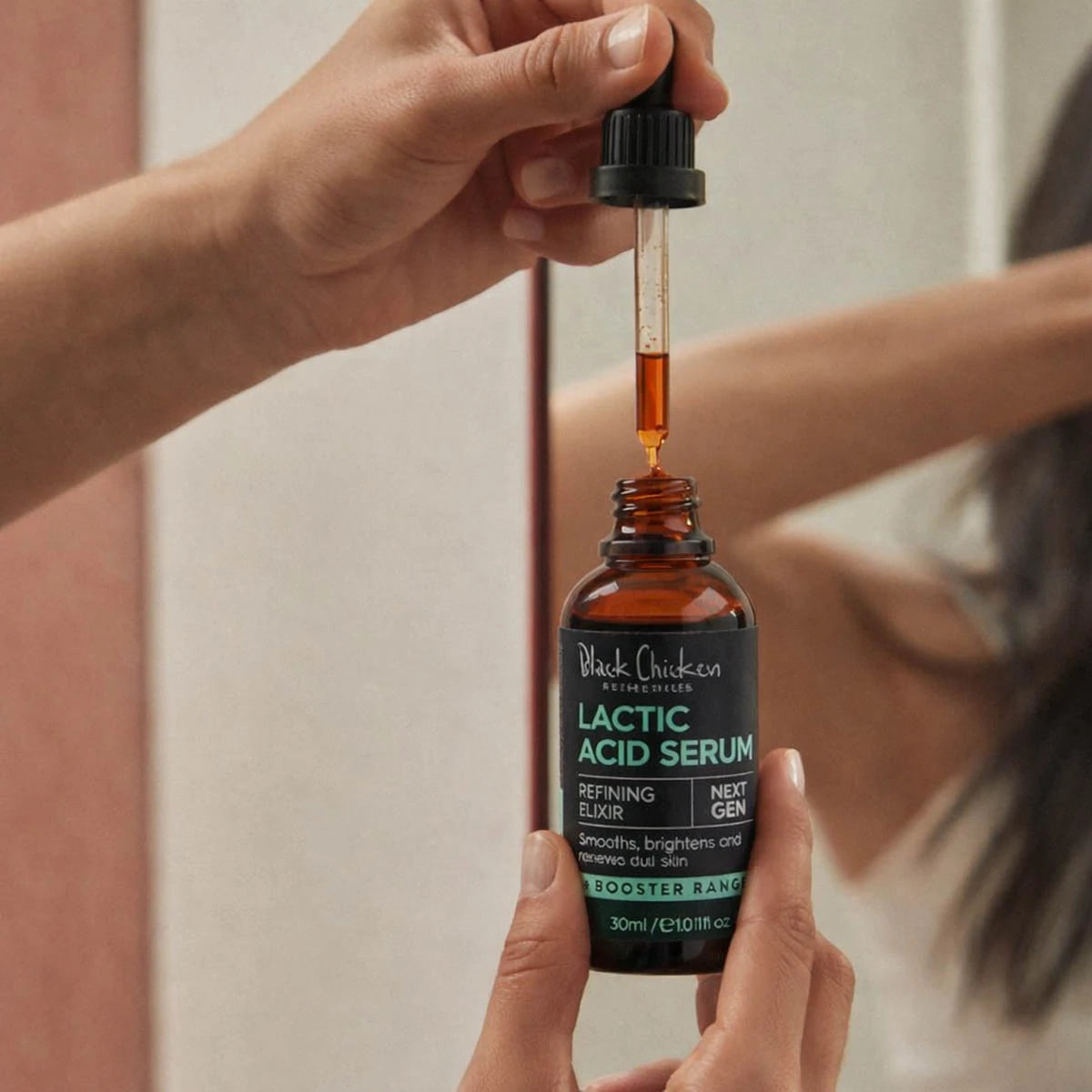 Person holding a bottle of Lactic Acid Serum with a dropper.