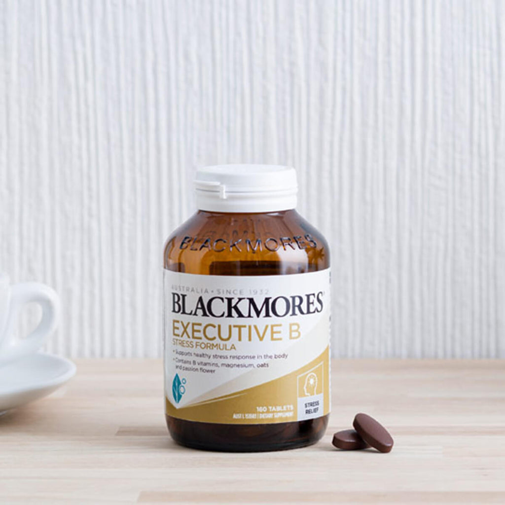Blackmores Executive B vitamins supplement bottle on a wooden surface with a white background.