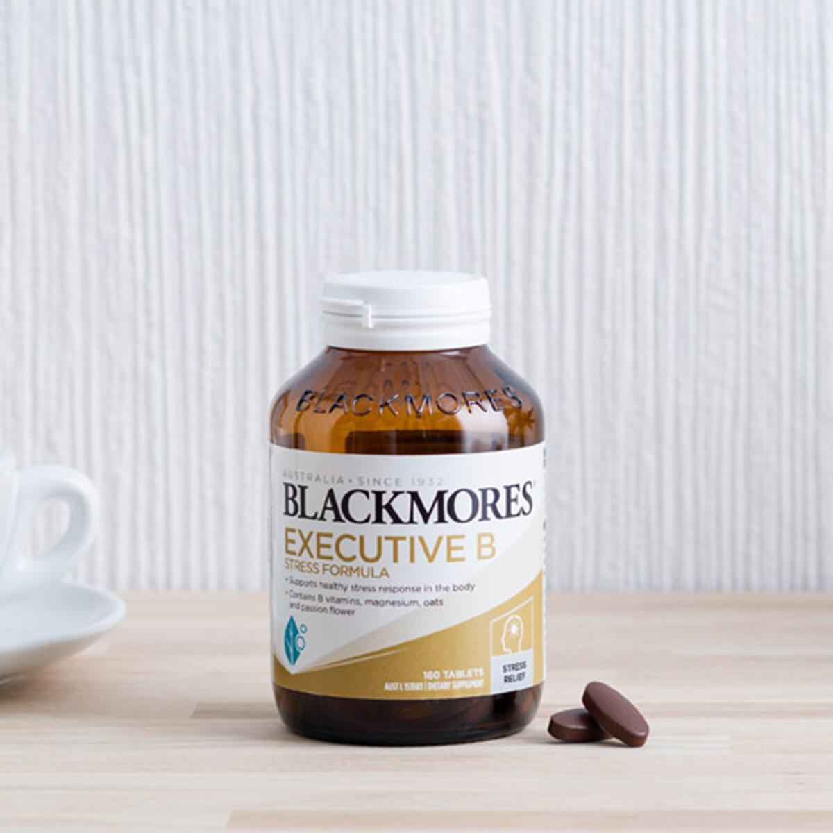 Blackmores Executive B vitamins supplement bottle on a wooden surface with a white background.