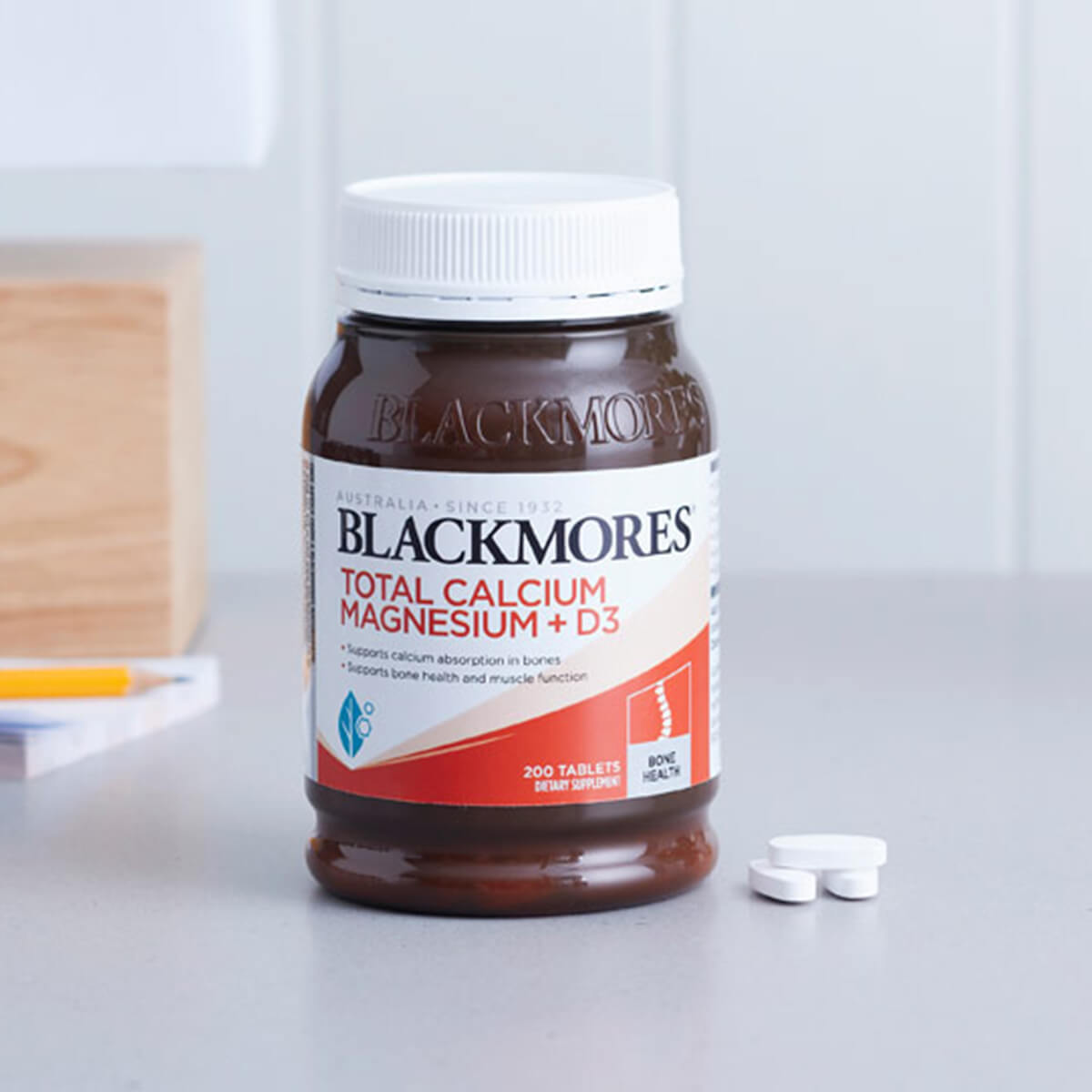 Jar of Blackmores supplement next to tablets on a white surface.