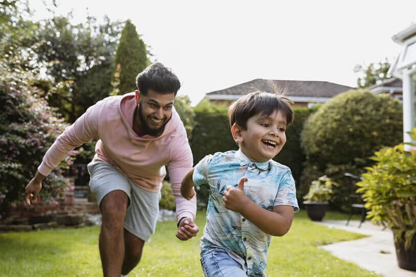 Dad playing tag with his son in backyard.