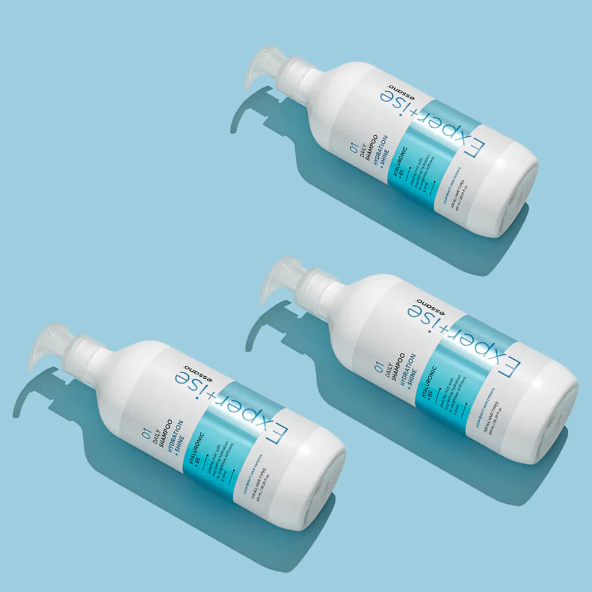 Three bottles of 'Expertise' shampoo on a light blue background.