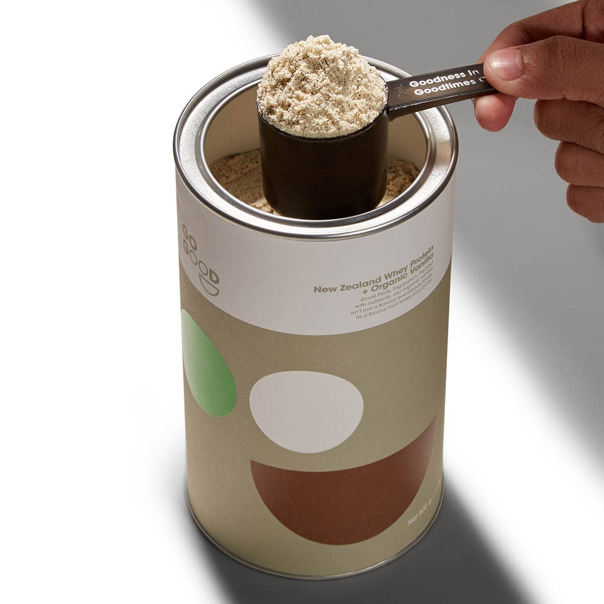 Canister of protein powder with a scoop being taken out.