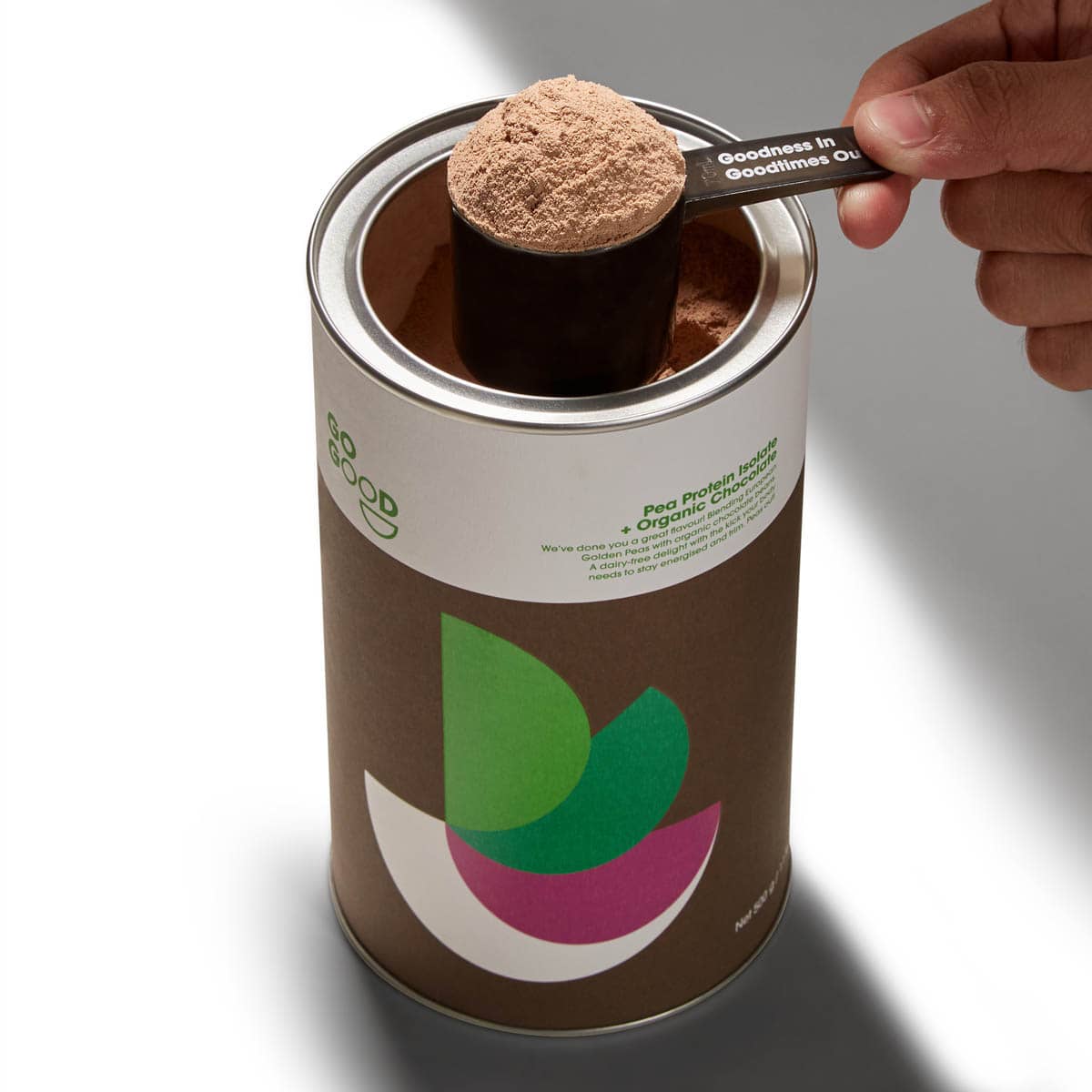 Person scooping brown powder from a can with a spoon.