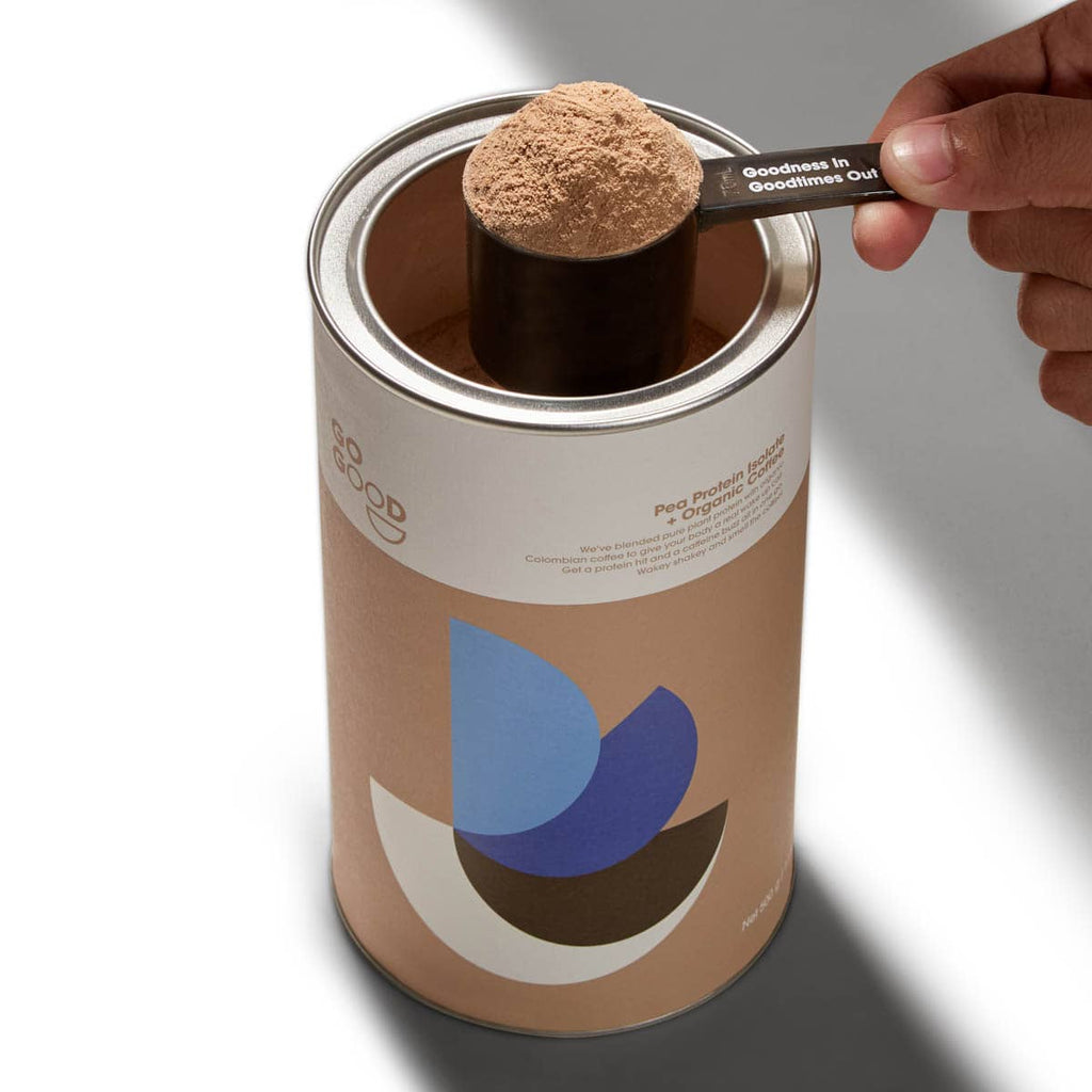 Person scooping protein powder from a canister with a spoon.