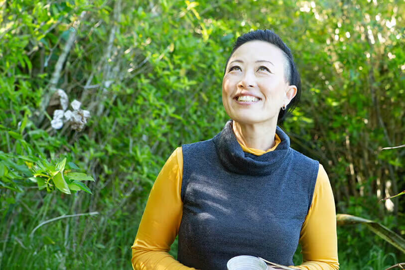 Middle-aged woman outside in forest setting.