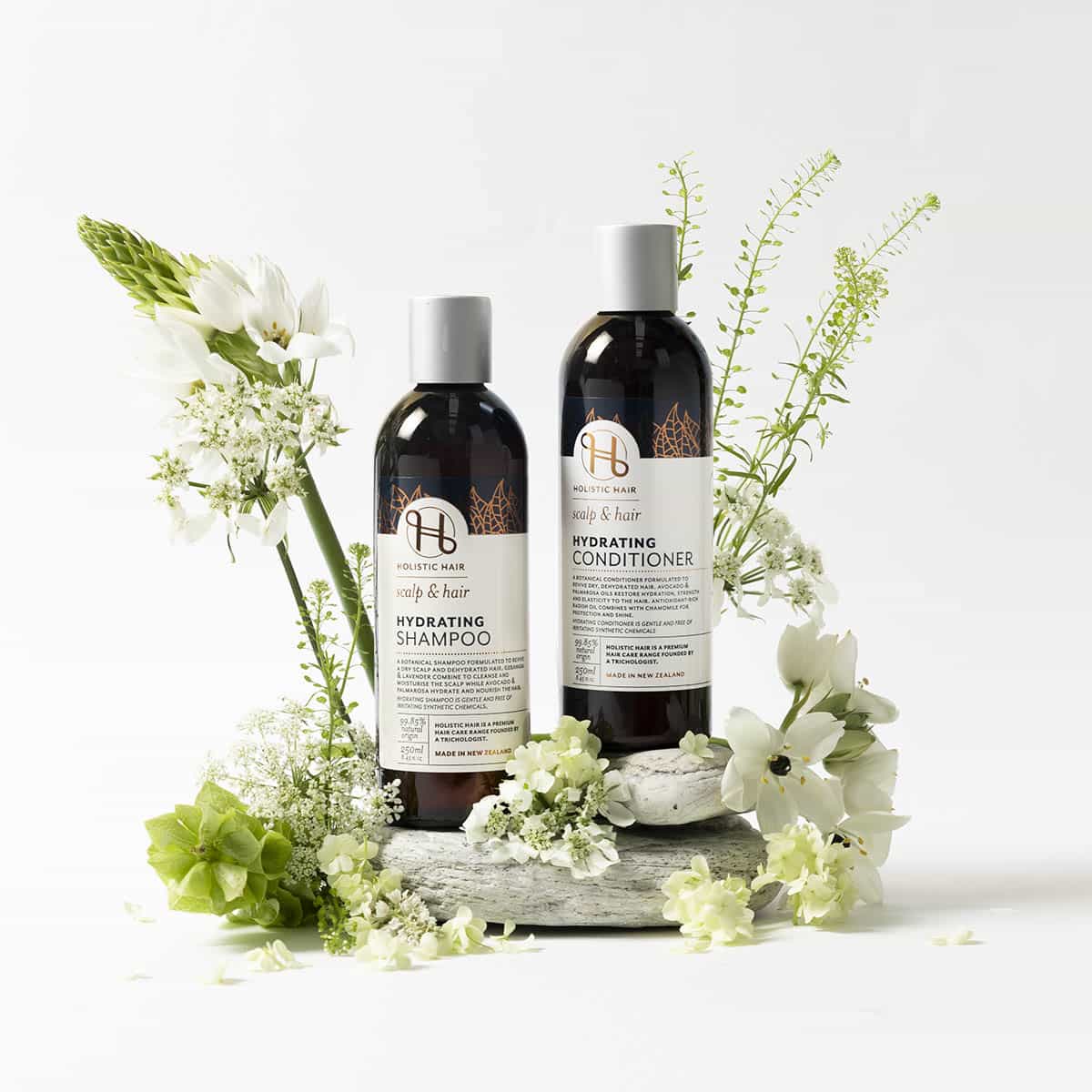 Two bottles of shampoo and conditioner with flowers on a white background