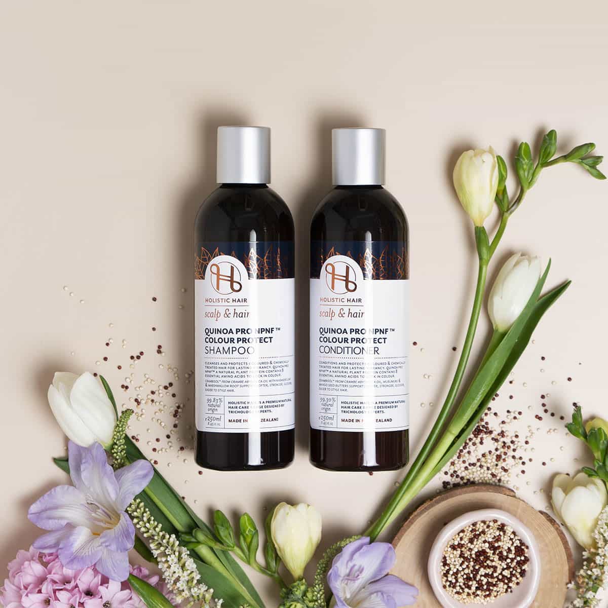 Two bottles of hair care products with flowers on a beige background