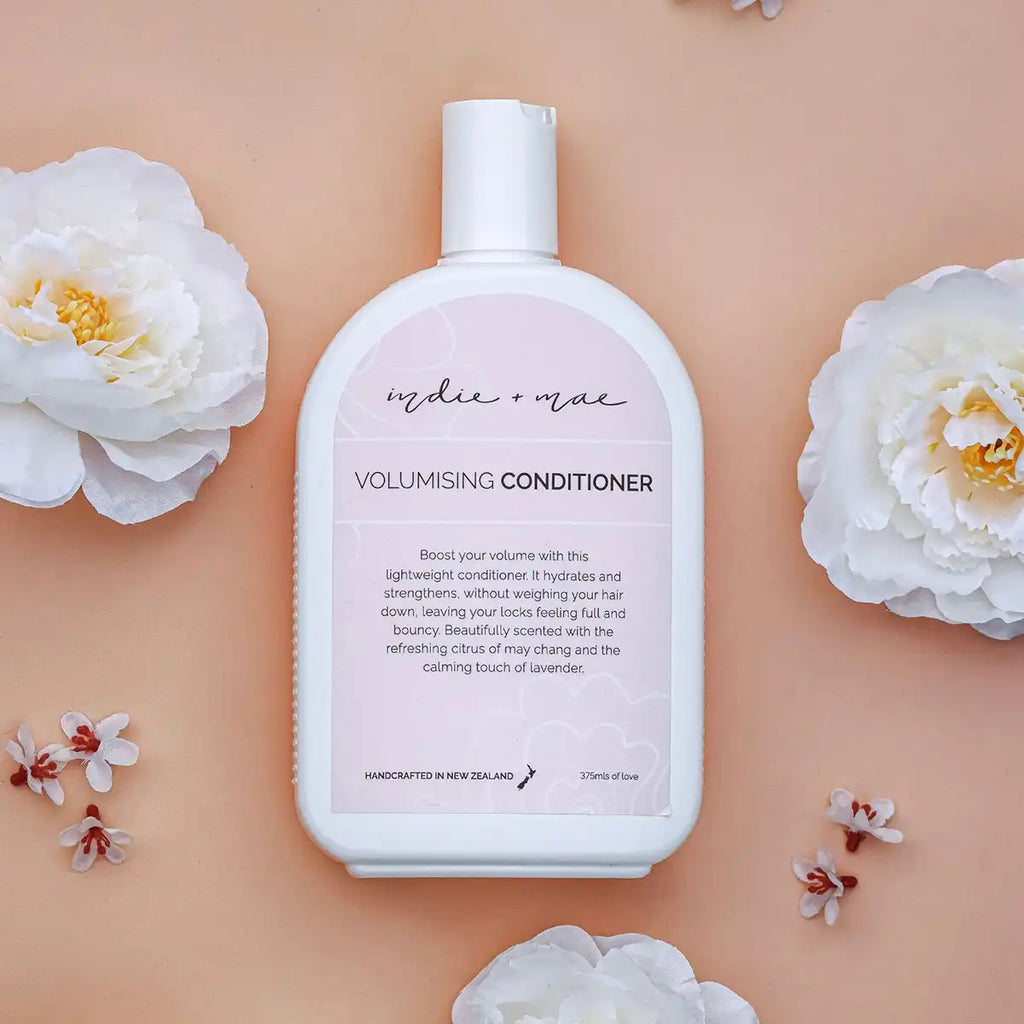 Volumising conditioner bottle with floral elements on a peach background.