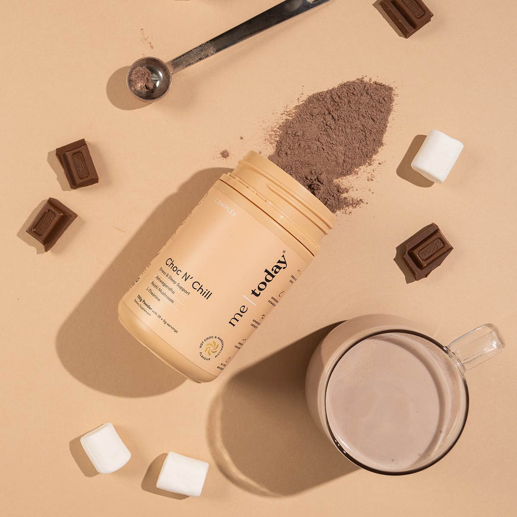 Container of 'me today' Choc N' Chill with powder spilling out, chocolate bars, and a mug on a beige background