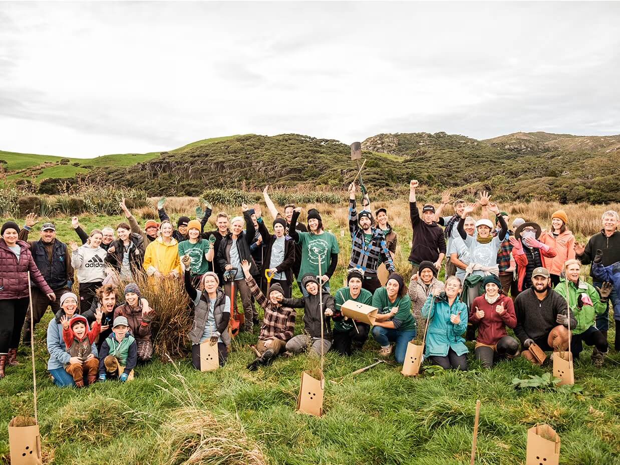 Group shot of tree planters in a field holding shovels.