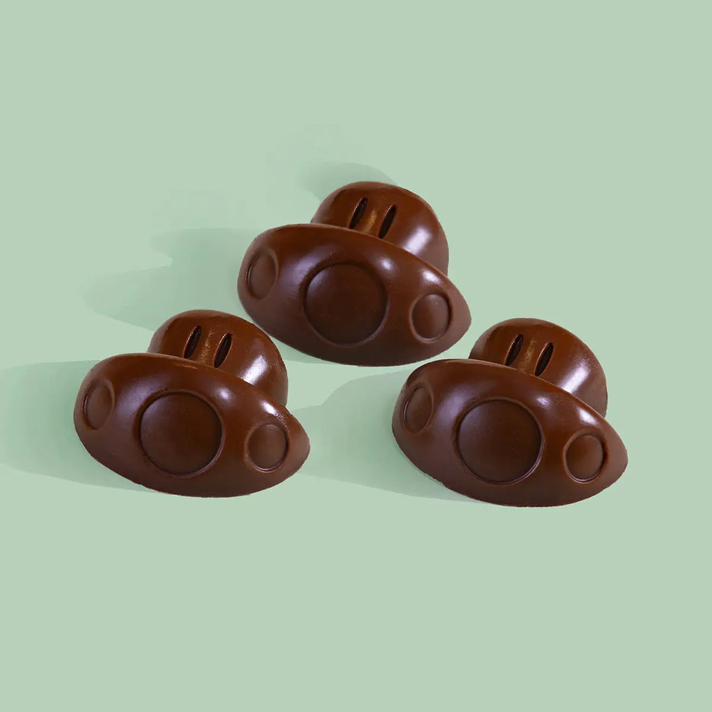 Three brown mushroom-shaped chocolates on a light green background.