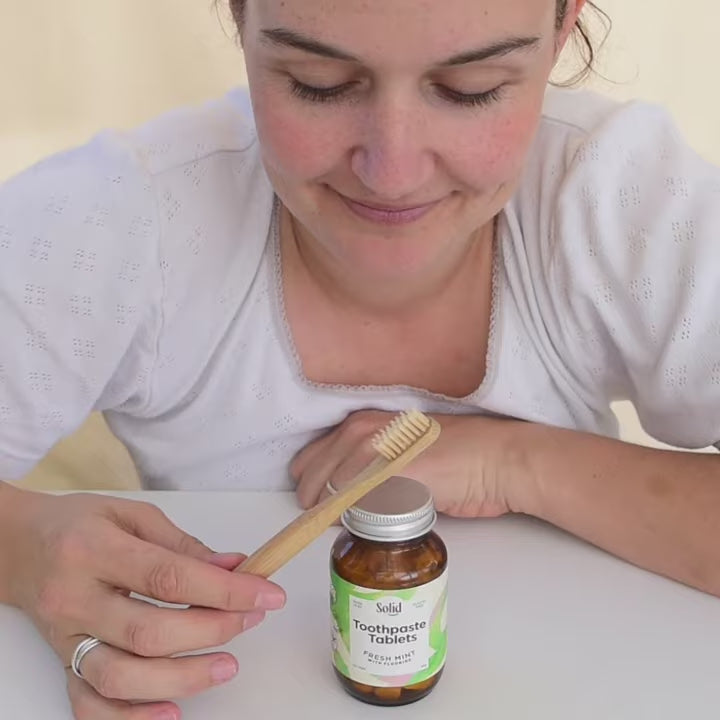 Person demonstrating how to use Solid's toothpaste tablets.