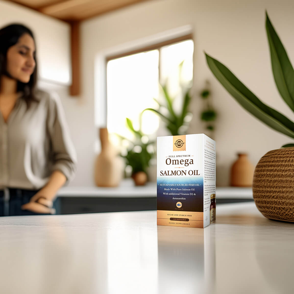 Omega Salmon Oil packaging on a kitchen counter with a blurred woman in the background.