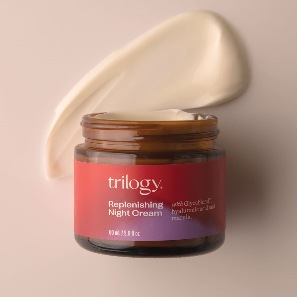 Jar of Trilogy Replenishing Night Cream with a beige applicator on a beige background.