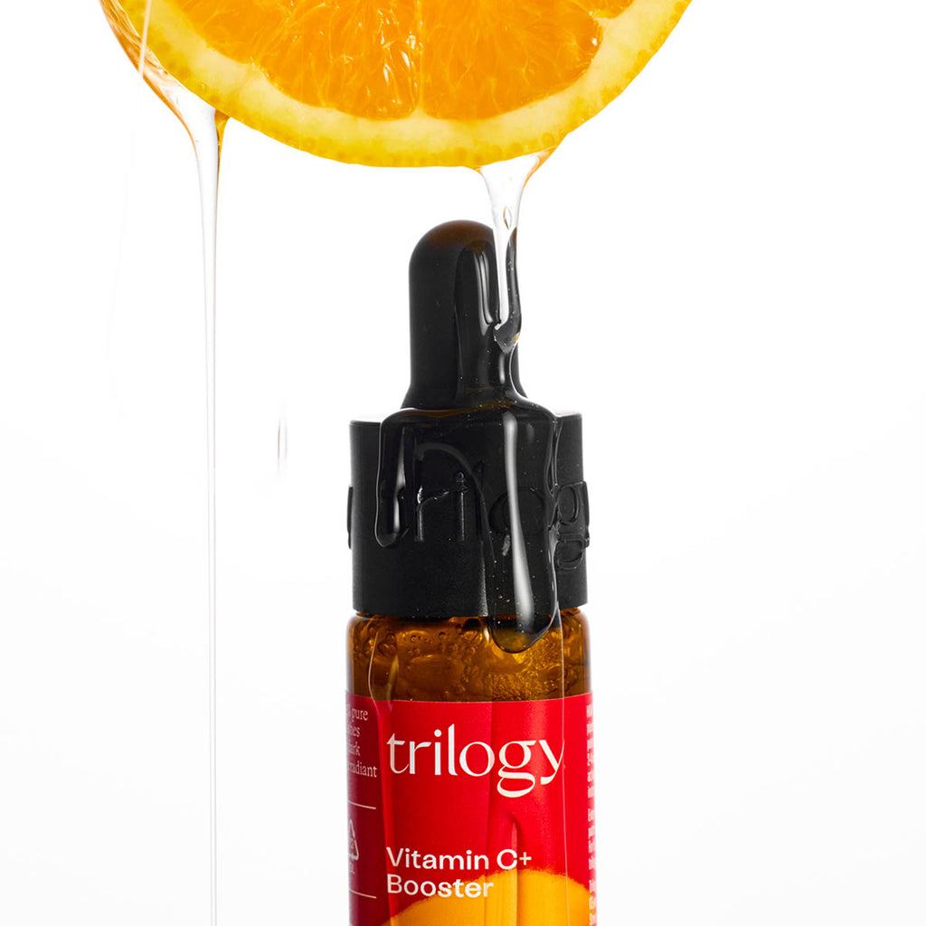 Trilogy Vitamin C+ Booster bottle with a dropper and orange slice on a white background