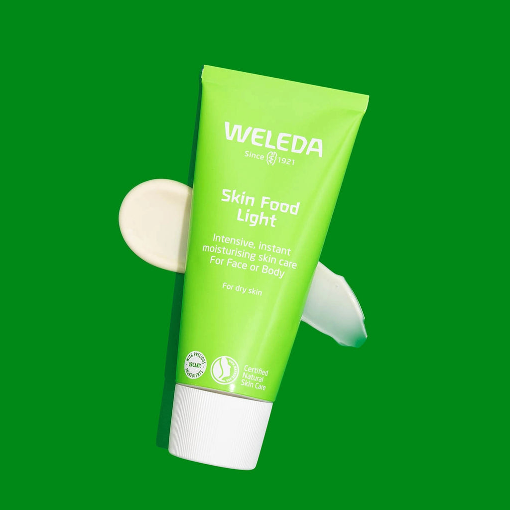 Green tube of Weleda Skin Food Light on a green background with a swatch.